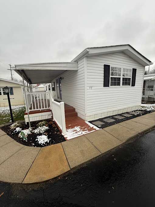 A white residence with a porch and snow on the ground.