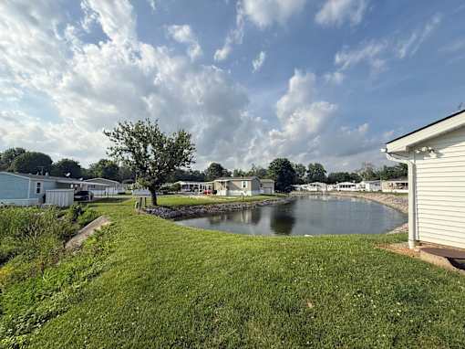 A serene landscape with a river, houses, and trees.