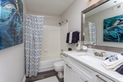 a bathroom with a white toilet next to a bathtub with a shower curtain