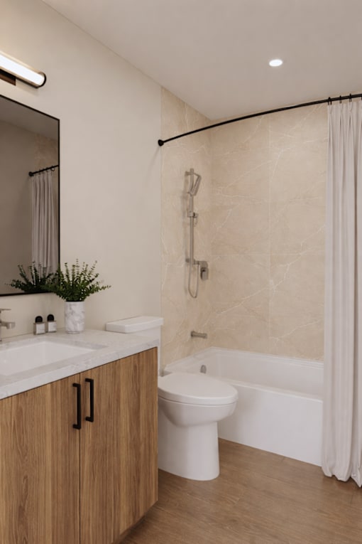 A modern bathroom with a white toilet, a sink, a mirror, and a bathtub with a shower curtain.