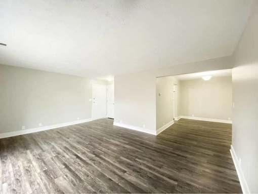A room with wooden flooring and white walls.