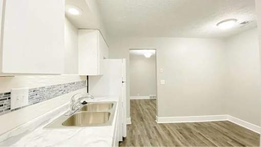 A kitchen with white cabinets and a stainless steel sink.