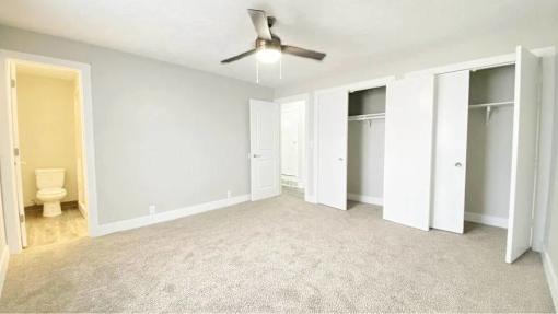 A room with a ceiling fan and carpeted floor.