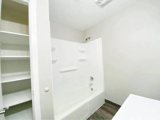 A white bathroom with a walk-in shower and a white table.