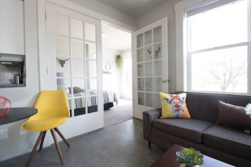 A yellow chair sits in a room with a brown couch and a coffee table.