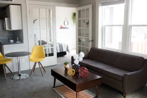 A living room with a brown couch, a yellow chair, and a coffee table.