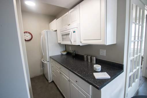 A kitchen with white cabinets and a black countertop.