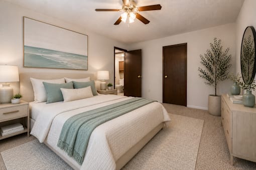 A bedroom with a large bed, a ceiling fan, and a painting on the wall.