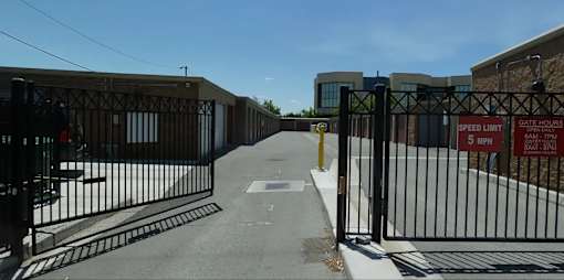 A black gate with a sign that says "SPEED LIMIT 5 MPH" is blocking the road.