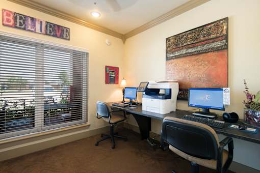 a home office with two computers and a printer on a desk
