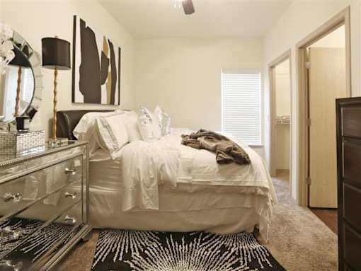 A bedroom with a white bed and a black and white rug.
