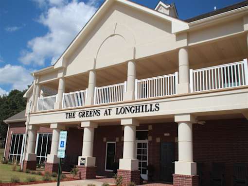 The Greens at Longhills is a building with a red brick exterior and a white overhang.