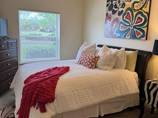 A bed with a red blanket and pillows in a room.