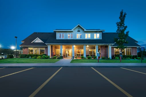 A large house with a parking lot in front.