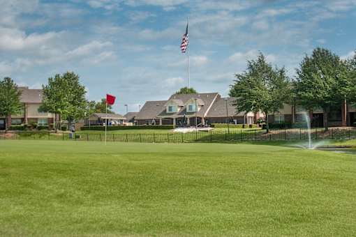 a large lawn in front of a the club house with a fountain