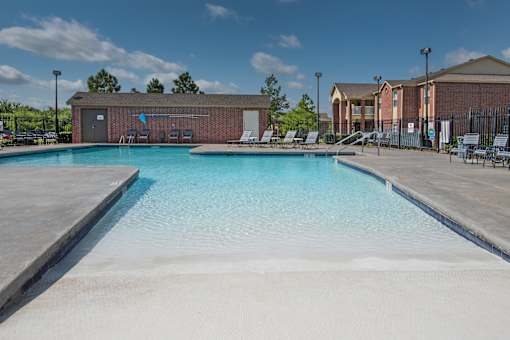 A swimming pool with a blue tinted water and a white sandy bottom.
