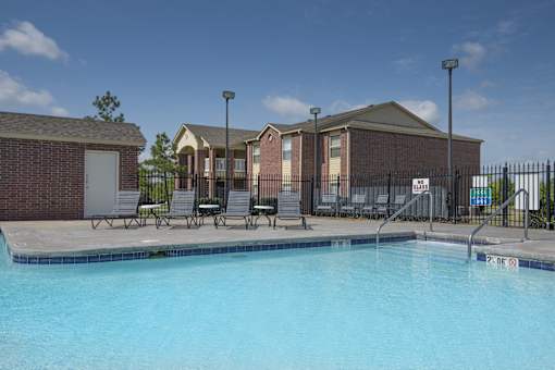 A swimming pool in front of a building with a fence around it.