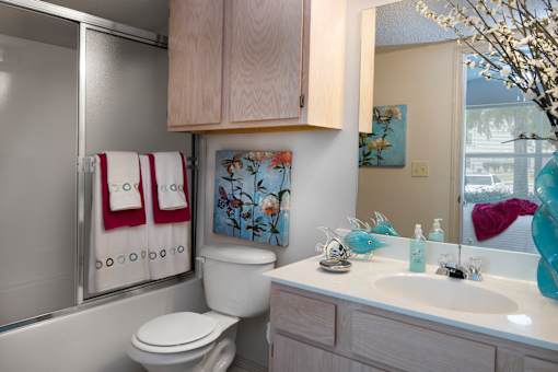 A bathroom with a toilet, sink, and a painting on the wall.