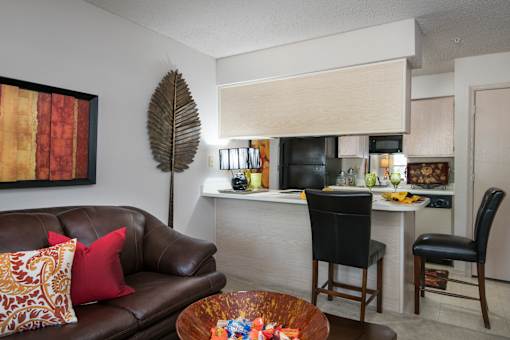 A brown leather couch with a red pillow and a brown wooden coffee table.