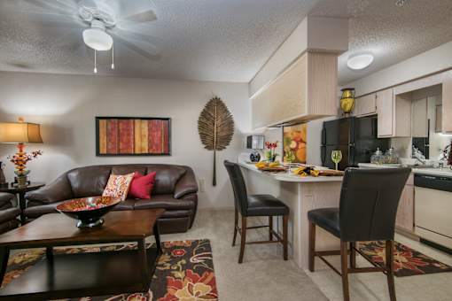 A living room with a brown couch and a dining table with chairs.