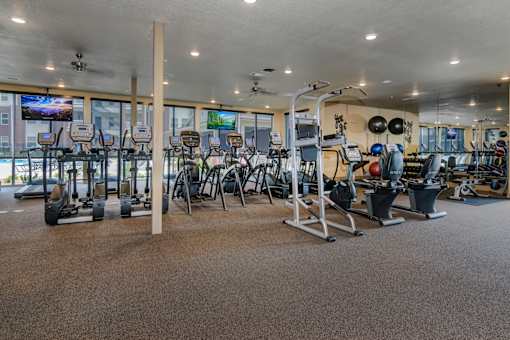 A gym with a variety of equipment including treadmills, weights, and exercise machines.