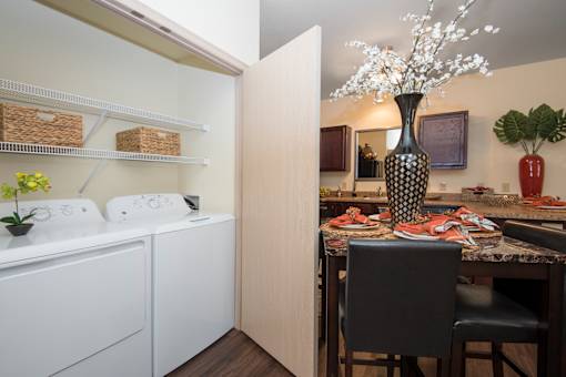 A kitchen with a white fridge, a black and white vase, and a dining table with chairs.