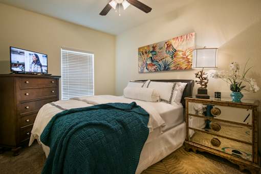 A bedroom with a bed, dresser, and ceiling fan.