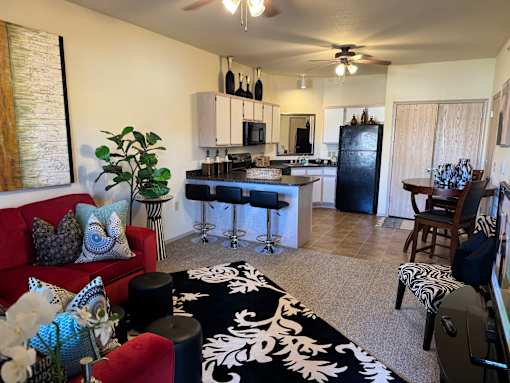 A living room with a red couch and a black and white rug.