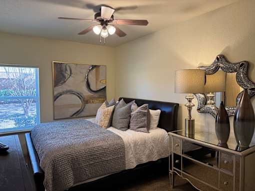 A bedroom with a bed, nightstand, and a painting on the wall.