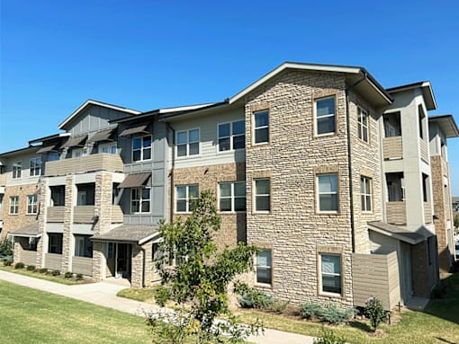A large apartment building with a mix of stone and siding exterior.