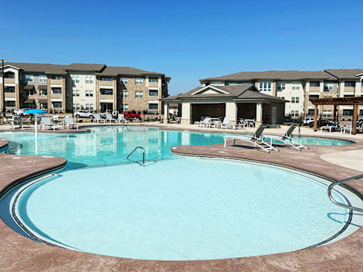 A large swimming pool in front of apartment buildings.