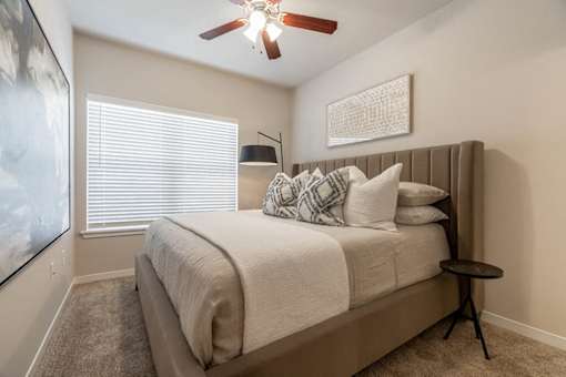 A bedroom with a bed, pillows, and a ceiling fan.