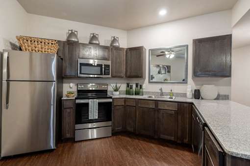 A kitchen with a refrigerator, oven, microwave, and sink.