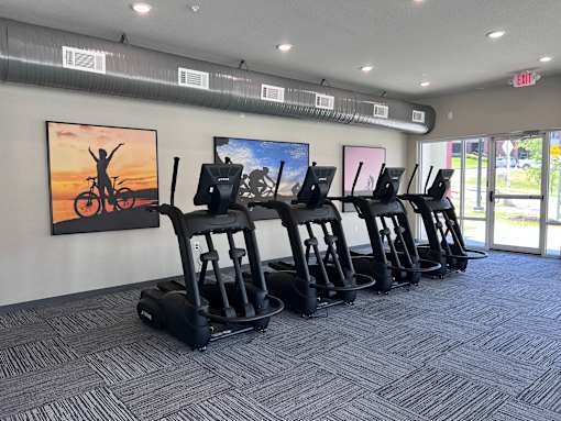 A gym with treadmills and a painting of a person on a bike on the wall.
