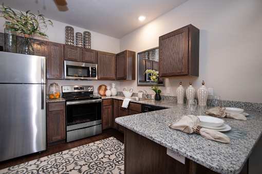 A kitchen with a refrigerator, microwave, oven, and a counter with plates and napkins on it.