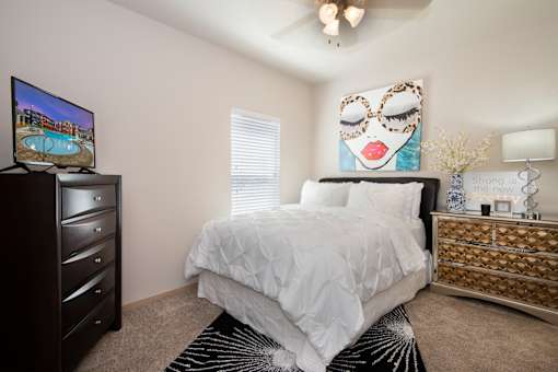 A bedroom with a large bed, a TV, and a dresser.
