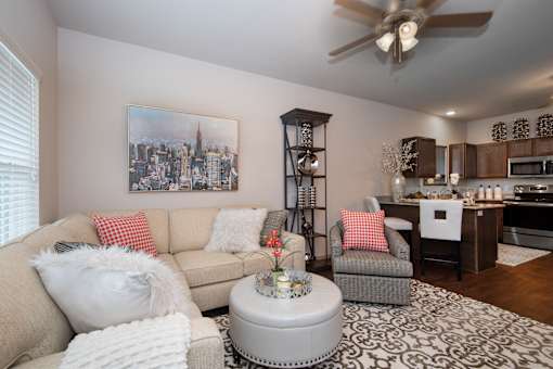 A living room with a beige couch, a grey armchair, a white coffee table, and a painting of a city skyline on the wall.