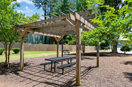 a picnic area with a bench and a pergola