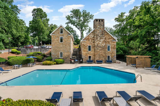 a swimming pool with chairs around it in front of a house