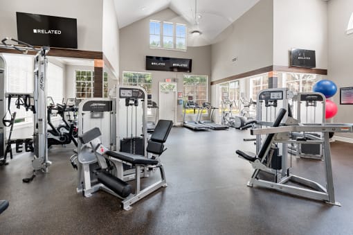 a gym with cardio equipment and weights in a building with a window