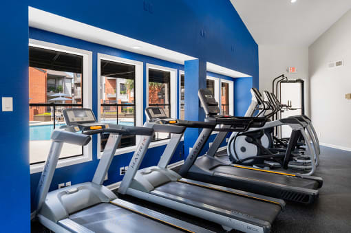 Gym with cardio equipment and windows with a pool