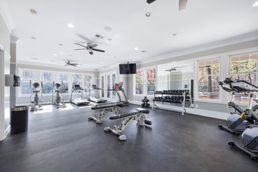 the home gym has plenty of exercise equipment and windows