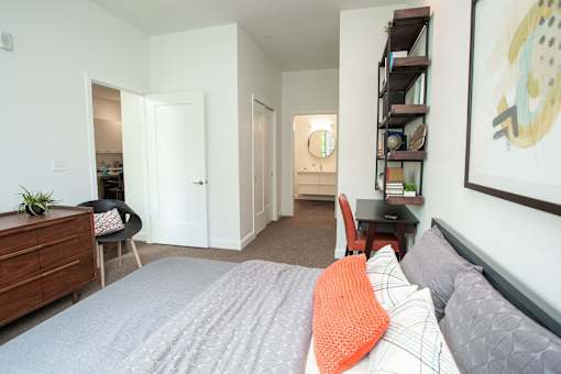 A bedroom with a bed, a chair, a dresser, and a painting on the wall.