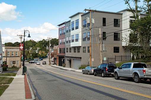 A street with cars parked on the side and buildings in the background.