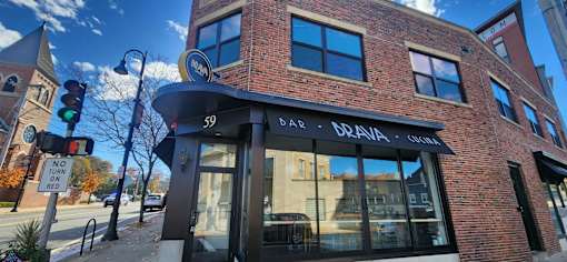 A brick building with a black awning and a sign that says "BRAVA" on it.