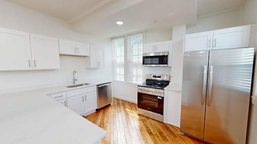 A kitchen with white cabinets and a stainless steel refrigerator.