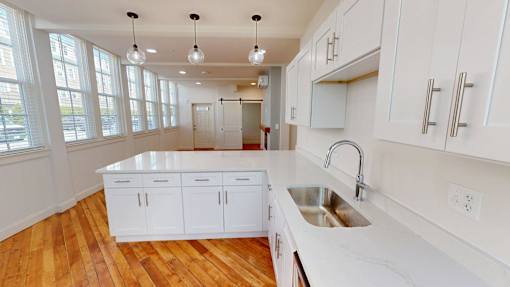 A kitchen with white cabinets and a wooden floor.