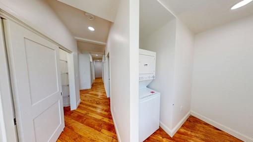 A hallway with a washing machine in the corner.