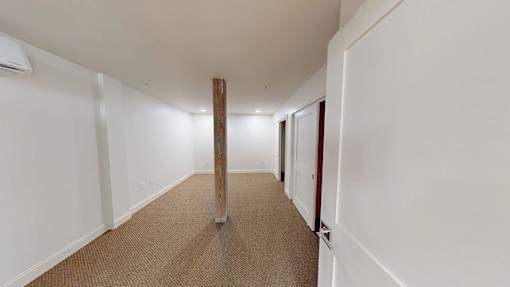 A long hallway with a carpeted floor and white walls.