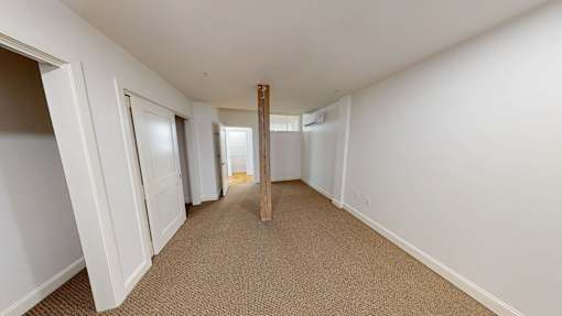 A long hallway with white walls and carpeted floor.